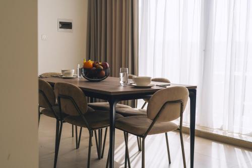 a dining room table with chairs and a bowl of fruit at The Valley Collection - Suite A22 in Xagħra
