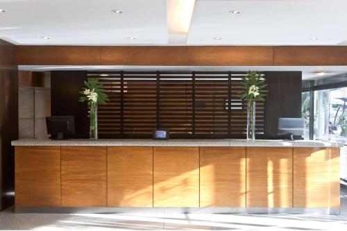 a lobby with a reception desk with two palm trees at NH Córdoba Panorama in Córdoba