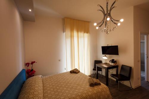a bedroom with a bed and a desk and a chandelier at B&B Corso Diaz in Ravenna