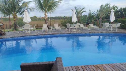 a large blue swimming pool with chairs and umbrellas at Seasonal Rental Itacimirim in Camacari