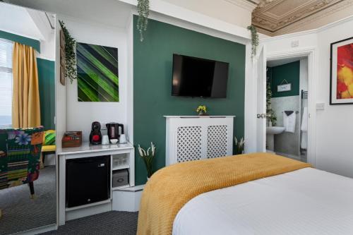 a bedroom with a bed and a tv on a wall at Glenholme Guest House - Room Only in Scarborough