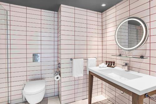 a bathroom with a toilet and a sink and a mirror at Radisson RED Hotel, Glasgow in Glasgow