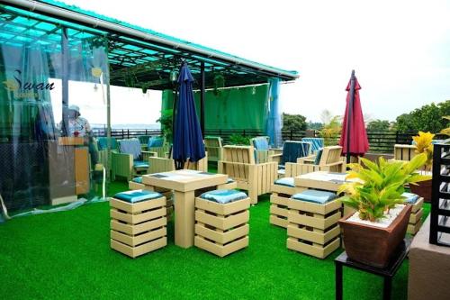 a patio with chairs and umbrellas on the grass at Swan Courts - Entebbe in Bugiri