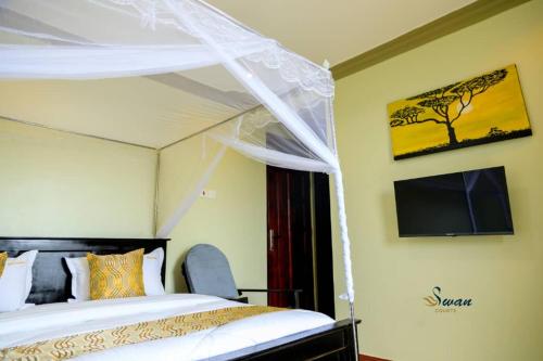 a bedroom with a canopy bed and a tv at Swan Courts - Entebbe in Bugiri