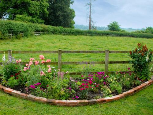 a garden with flowers in front of a fence at The Byre in West Stour