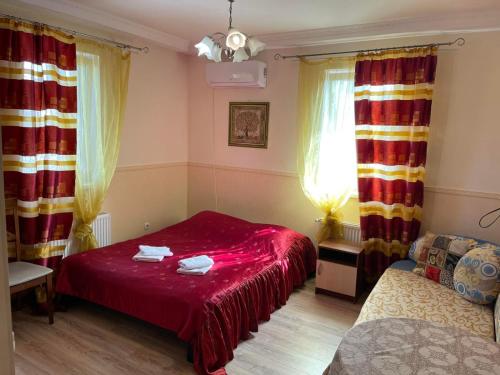a bedroom with a red bed and a couch at Hotel Domashnii in Zhytomyr