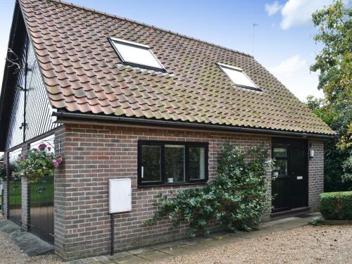 ein Backsteinhaus mit drei Fenstern und einem Dach in der Unterkunft Broad Cottage Boathouse in Ranworth