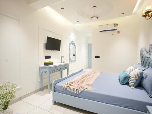 a white bedroom with a bed and a desk at The Garden Hotel in Ahmedabad