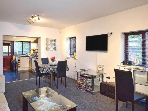 a living room with a table and a tv on the wall at South Lodge Cottage in Standish