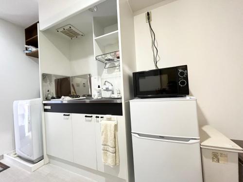 a kitchen with a white refrigerator and a microwave at 駅南うちやまビル03 in Fukuoka