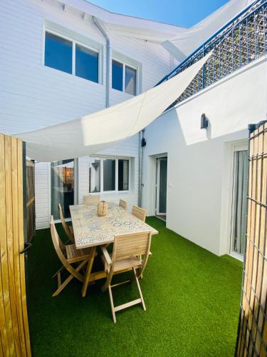 d'une terrasse avec une table et des chaises sur gazon. dans l'établissement Le petit Desbiey, à Arcachon