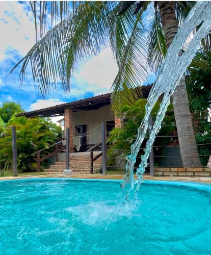 a swimming pool with a fountain in front of a house at Casa Florida in Beberibe