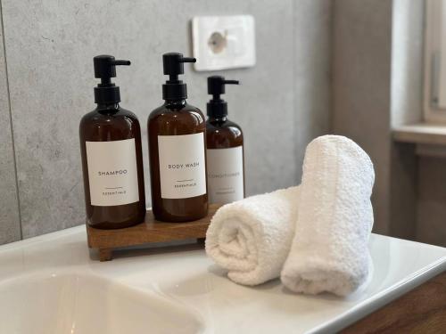 three bottles of soap and a towel on a bathroom sink at Casa Angelina in Barlassina