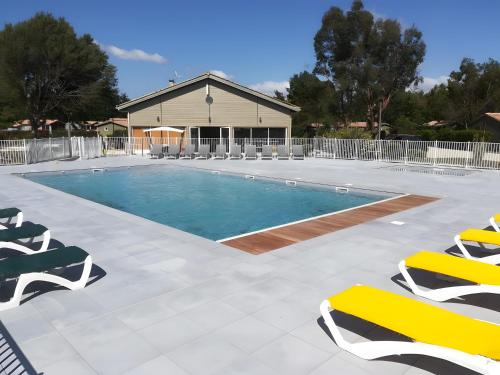 une piscine avec des chaises longues et une maison dans l'établissement Chalet parc nature océan, à Hourtin