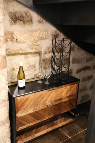 a bottle of wine and two wine glasses on a dresser at Love House - Maison entière et son jardin - Rare à Paris in Paris