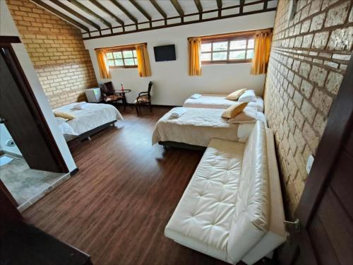 a room with two beds and a couch in it at Hotel San Luis Sachica ng in Sáchica