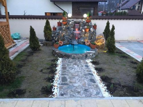 a garden with a fountain in the middle of a yard at Pensiune Matrix in Curtea de Argeş