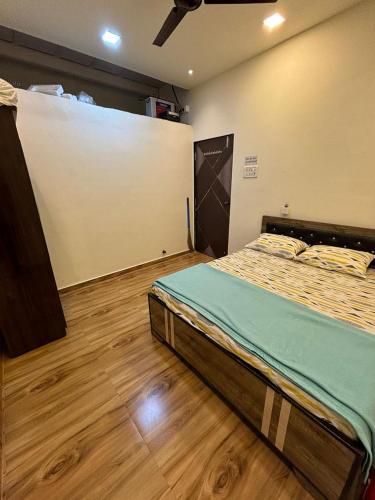 a bedroom with a bed in a room with wooden floors at Nirvana Stays Shirol Shahpur in Khardi
