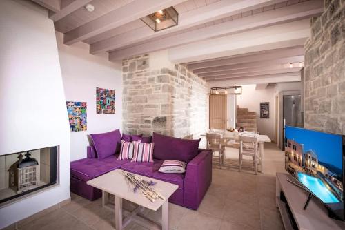 sala de estar con sofá púrpura y chimenea en Phaistos Villas - Private Pool Luxury Retreats, en Sívas