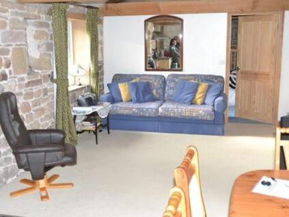 Una sala de estar con un sofá azul y una silla. en The Bird Bath - Cottage, en Wreay
