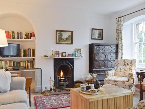 ein Wohnzimmer mit Kamin und einem Stuhl und einem Tisch in der Unterkunft Jubilee Cottage in Enstone