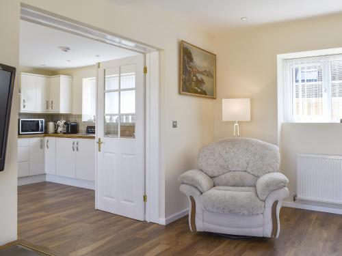 a living room with a chair and a kitchen at Stars Cottage in Moreton