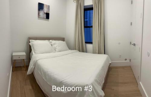 a bedroom with a bed with white sheets and a window at Modern, New 3 bed, 2 bath Apt near Manhattan in Jersey City