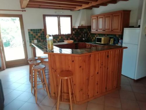 une cuisine avec un grand îlot en bois et des tabourets de bar dans l'établissement Au pied de la dune, agréable maison T5 et jardin, à Moliets-et-Maa