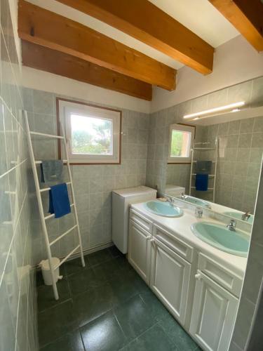 une salle de bain avec deux lavabos et un miroir dans l'établissement Au pied de la dune, agréable maison T5 et jardin, à Moliets-et-Maa