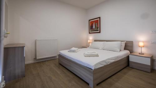 Un dormitorio con una cama con dos mesitas de noche y dos lámparas. en Italianway - Vat 52, en Udine