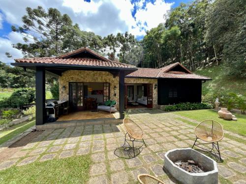 una casa con patio con sillas en el patio en Casa 04 Vale Boa Vista - Casa Charmosa com 3 Suítes e Acesso à Área de Lazer Completa de Condomínio, en Teresópolis