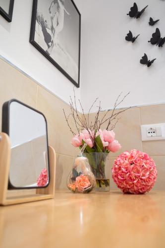 a table with a mirror and a vase of pink flowers at lachiocciola - Centro storico di Imola, autodromo e Formula 1 in Imola