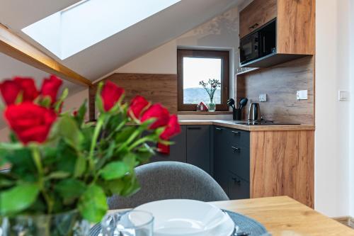 a kitchen with a table and a vase of red roses at Apartamenty Wisła Krzywa 8, wanna z hydromasażem, basen zewnętrzny in Wisła