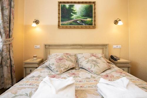 a bed with two pillows and a picture on the wall at Status Hotel in Lviv