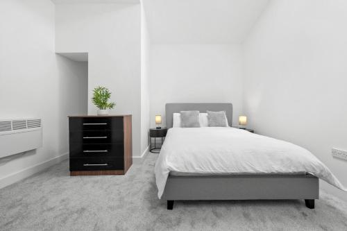 Un dormitorio con una cama y una cómoda con dos lámparas. en Modern 2BD City Apartment, en Warrington