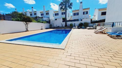a swimming pool in front of a white building at Albufeira Home Paderne in Paderne