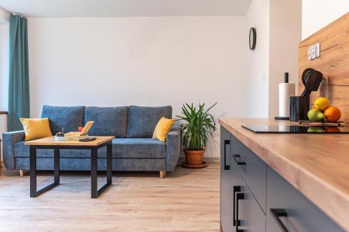 a living room with a blue couch and a table at Apartamenty Wisła Krzywa 8, wanna z hydromasażem, basen zewnętrzny in Wisła