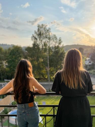two women standing on a railing looking out at a park at Apartamenty Wisła Krzywa 8, wanna z hydromasażem, basen zewnętrzny in Wisła
