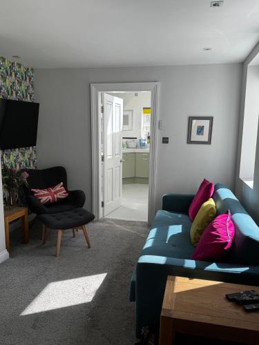a living room with a blue couch and a chair at Courtyard Mews - 2 large en suite bedrooms, Garden - Harrogate Holiday Apartments in Harrogate