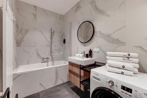a white bathroom with a tub and a washing machine at Scala City Center Magic Apartments with Parking by Lion Apartments in Gdańsk