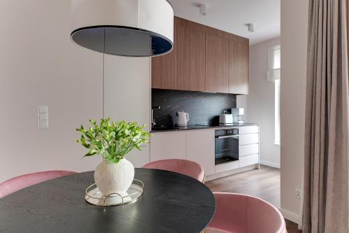 a kitchen with a black table and pink chairs at Scala City Center Magic Apartments with Parking by Lion Apartments in Gdańsk