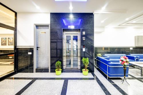 an elevator lobby with blue chairs and plants at Hotel Dream World - Free Airport Drop in New Delhi