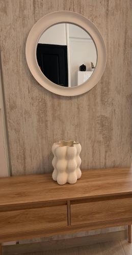 a round mirror above a table with a vase on it at CYRUS H-Housse cœur de ville in Pointe-à-Pitre