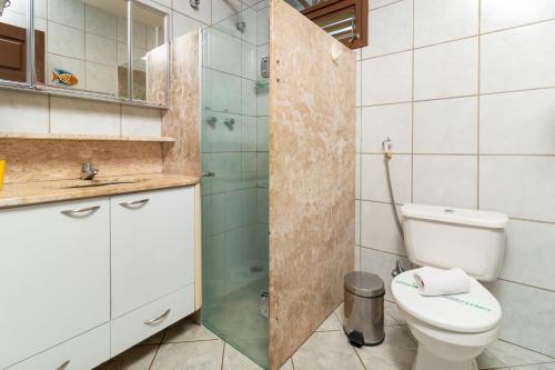 a bathroom with a toilet and a glass shower at Pousada da Terra in Natal