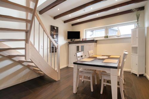 a dining room with a table and chairs and a staircase at Ferienhaus Martje in Hennstedt