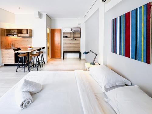 ein weißes Schlafzimmer mit einem großen Bett und einer Küche in der Unterkunft Athens Studios in Athen