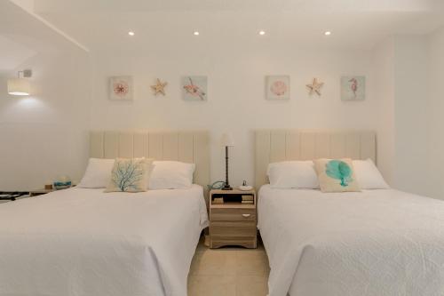 two beds sitting next to each other in a bedroom at Cancun Hotel Zone -2 BR Beachfront, Bright and Spacious in Cancún