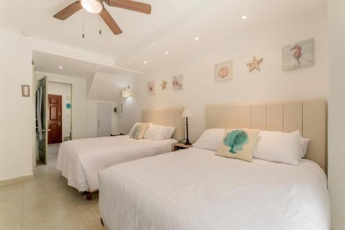 two beds in a bedroom with white walls and a ceiling at Cancun Hotel Zone -2 BR Beachfront, Bright and Spacious in Cancún
