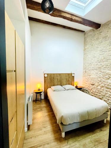 une chambre avec un lit et un mur de briques dans l'établissement L'Atelier - Coeur de ville, à La Rochelle