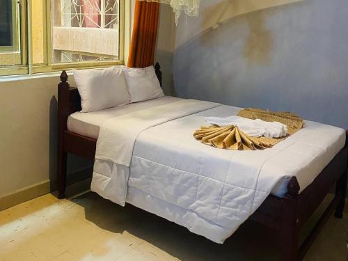 a bed with white sheets and a basket on it at Elgon Palace Hotel - Mbale in Mbale